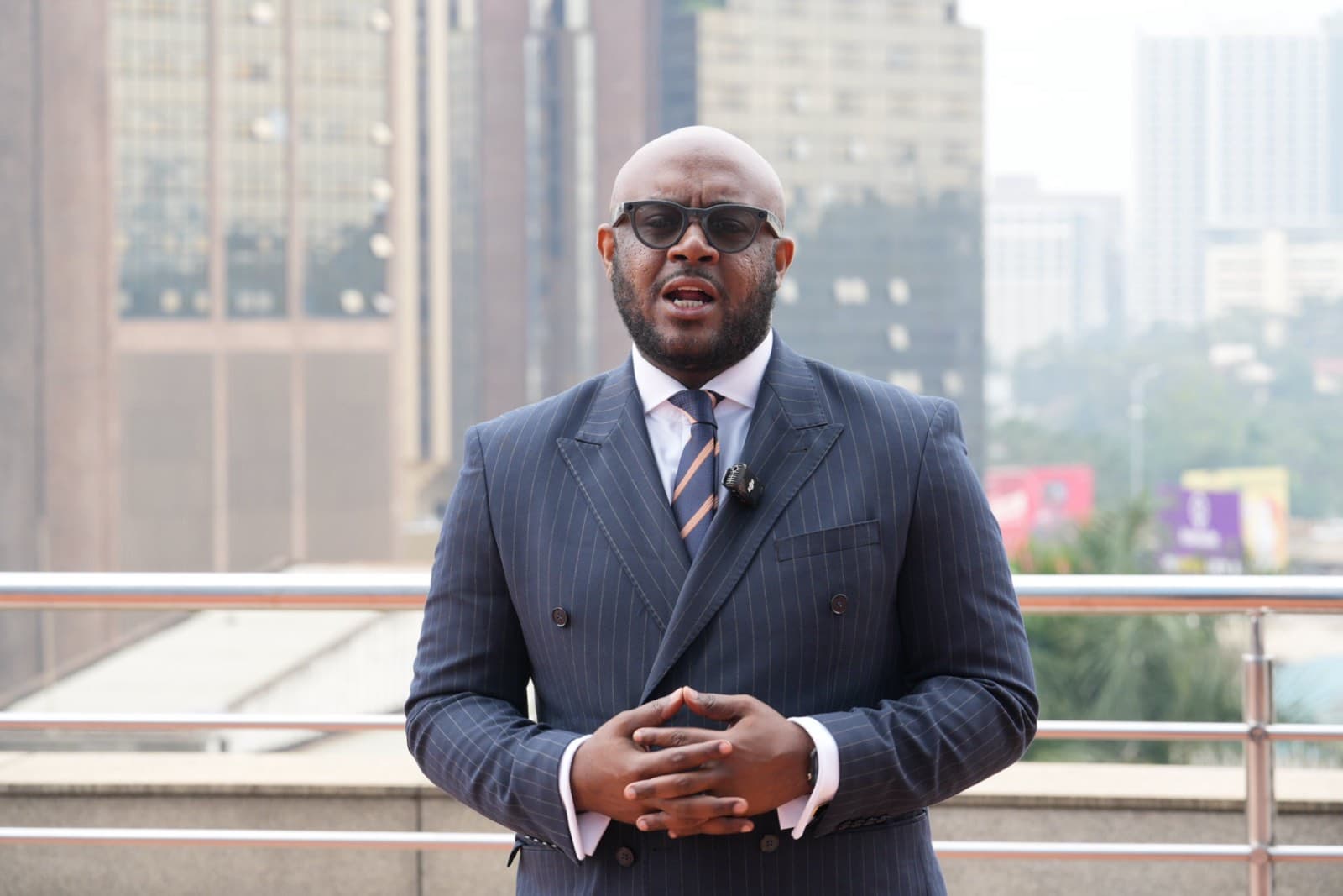 A leader speaking at the summit, city skyline behind